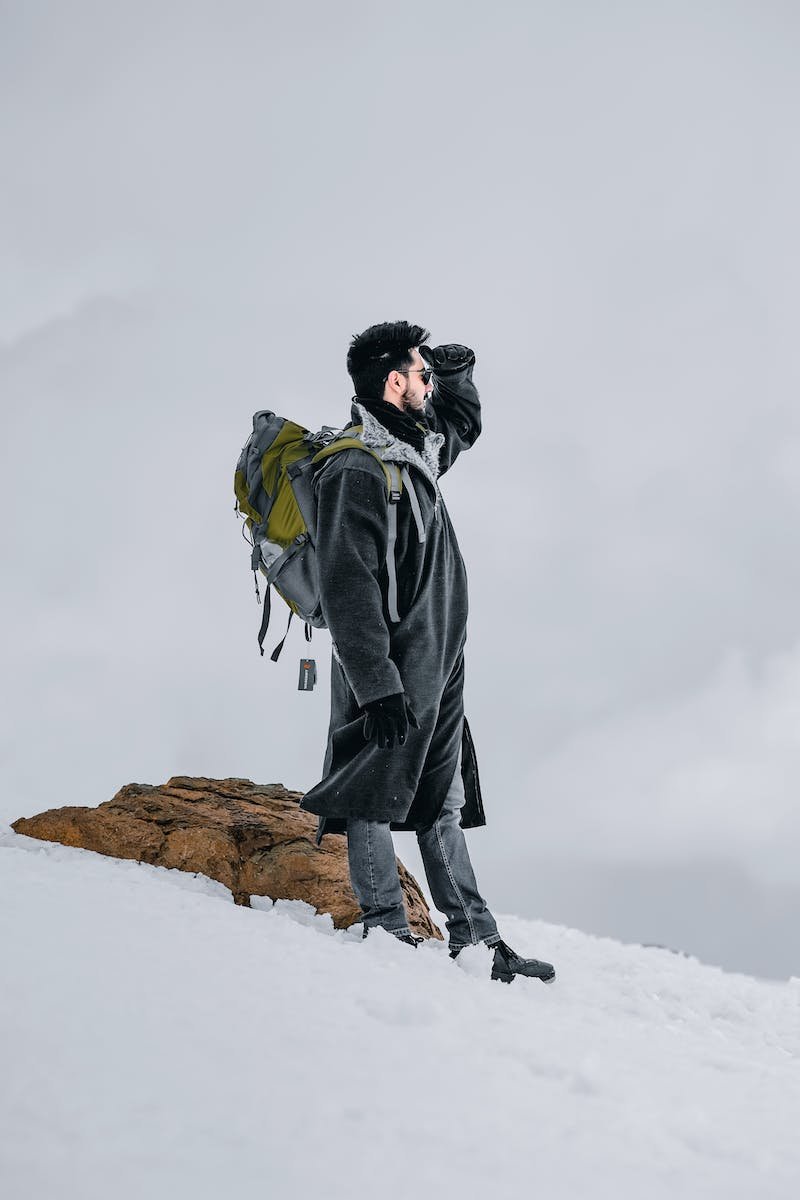 Man in Black Jacket Standing on Mountain Slope Covered in Snow